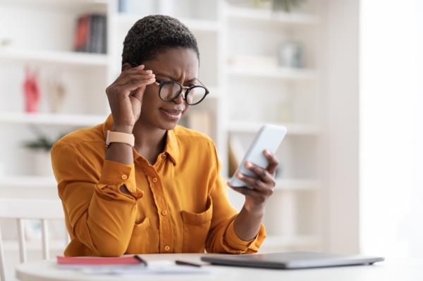 A young woman looking at her phone with a co<em></em>nfused look on her face after receiving a text message