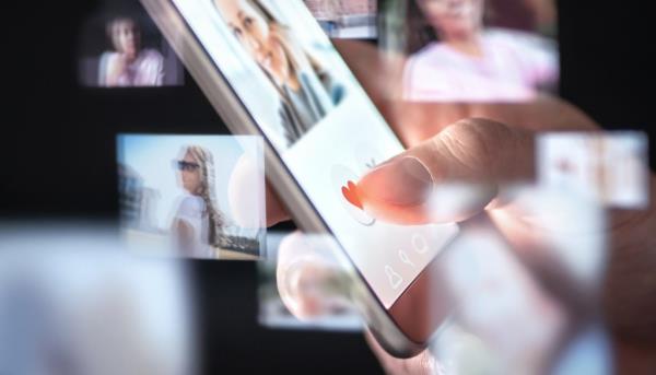 Man using a dating app on his smartphone, browsing through photos of women