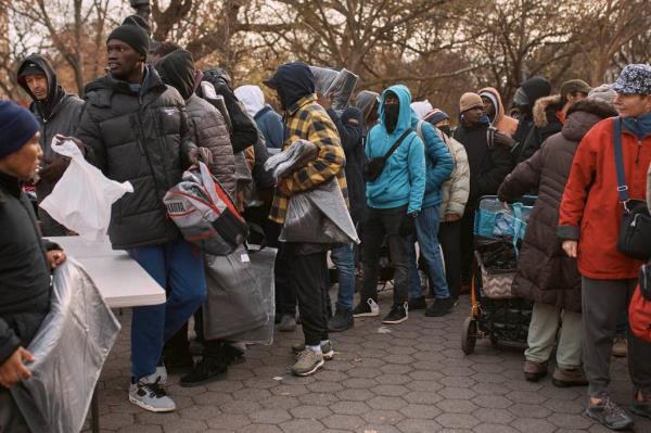 Migrants lined up outside many wearing winter coats