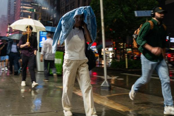 NEW YORK, NEW YORK - AUGUST 06: People walk through the rain in Manhattan as a severe storm moves through the area in the early evening on August 06