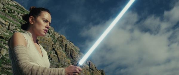 Daisy Ridley as Rey holding a lightsaber in 'Star Wars: The Last Jedi'