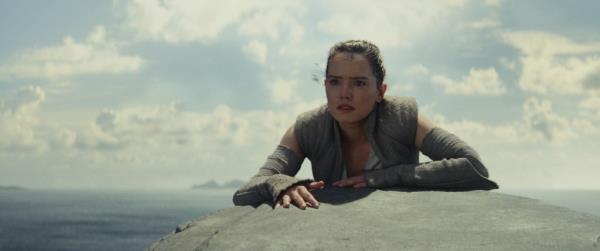 Daisy Ridley as Rey in Star Wars: The Last Jedi, leaning on a rock