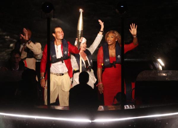 Rafael Nadal and Serena Williams holding the Olympic torch on a boat on the Seine River during the opening ceremony of Paris 2024 Olympics