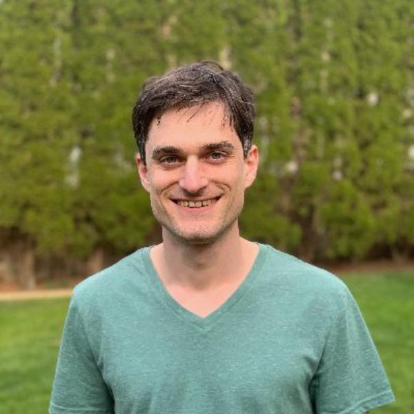 John Schulman smiling in front of a green field, now working at OpenAI rival Anthropic