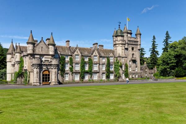 Balmoral Castle, a Scottish baro<em></em>nial revival style structure with towers, set amidst lush grounds in summer, the royal family's summer residence in Aberdeenshire, Scotland.