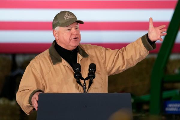 Minnesota Governor Tim Walz speaking at a podium with micropho<em></em>nes and a flag behind him at Dutch Creek Farms