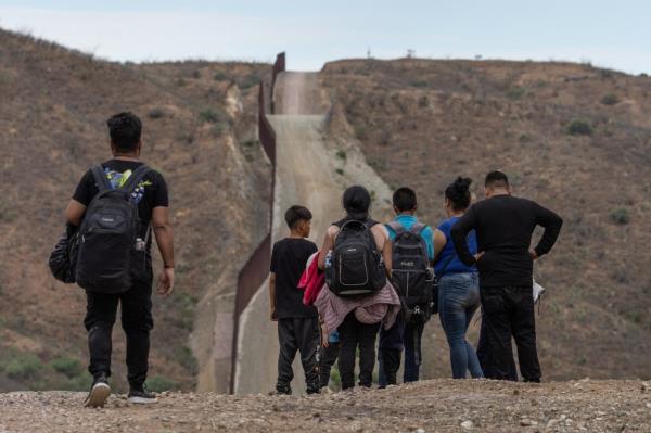 The Border Wall is seen in the background as migrants from South and Central America look to surrender to immigration officials after crossing into the United States from Mexico in Ruby, Arizona, U.S., June 24, 2024.