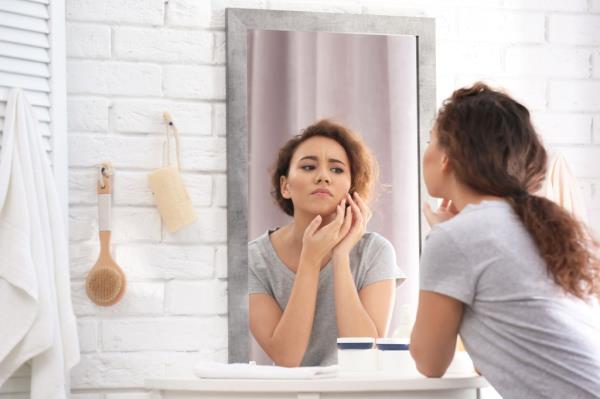 A woman noticing a pimple. 