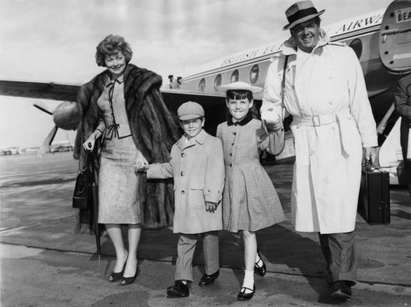 Lucille Ball and Desi Arnaz with their children Lucie and Desi Jr in 1959 smiling by a plane. 