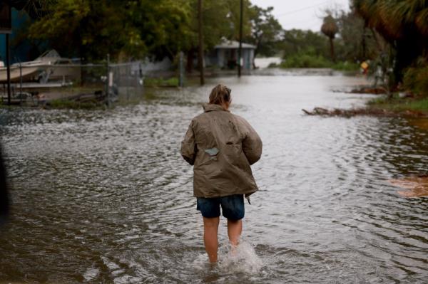 A man walking through a flooded street in Cedar Key, Florida during Hurricane Debby on Aug. 5, 2024.