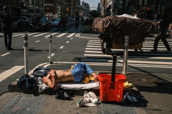 Vagrant sleeps on the sidewalk in Times Square.