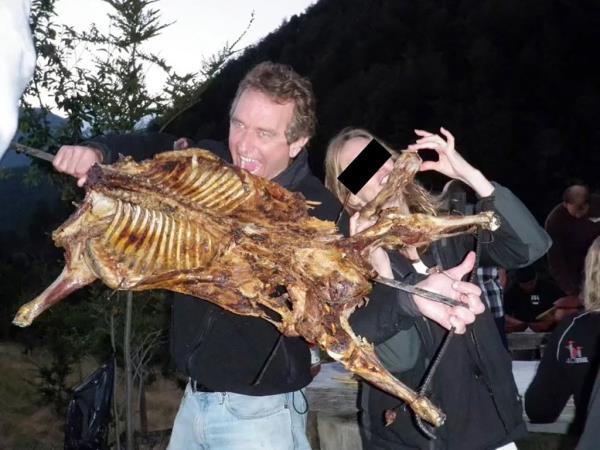 RFK Jr and a woman hold a barbecued carcass. 