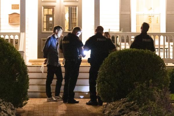 Several East Hampton Police Officers speaking with restaurant owner Scott Sartiano outside his establishment at night