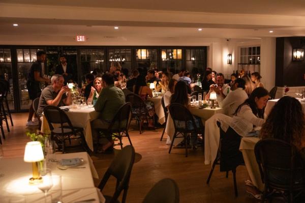 A group of people enjoying dinner at The Hedges Inn in East Hampton, presented by American Express Centurion X Sartiano