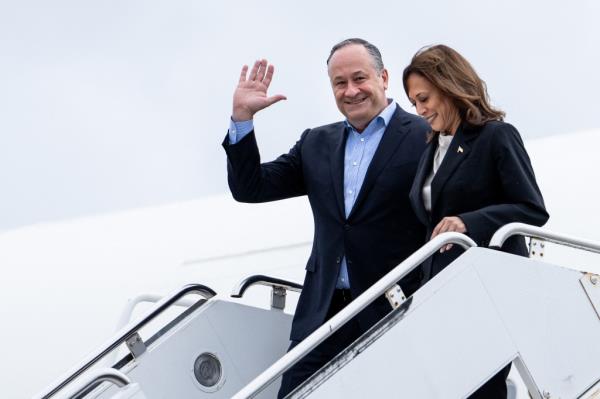 Doug emhoff waving as he and kamala harris get off a plane