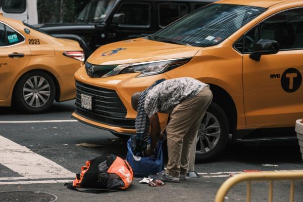 A homeless man goes through belo<em></em>ngings I the street by Port Authority Bus Terminal in midtown Manhattan. 