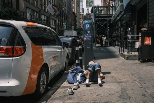 A person lays on the ground by a BRC van outside of the Housing Works harm reduction center on 37th street and 8th avenue in midtown Manhattan.