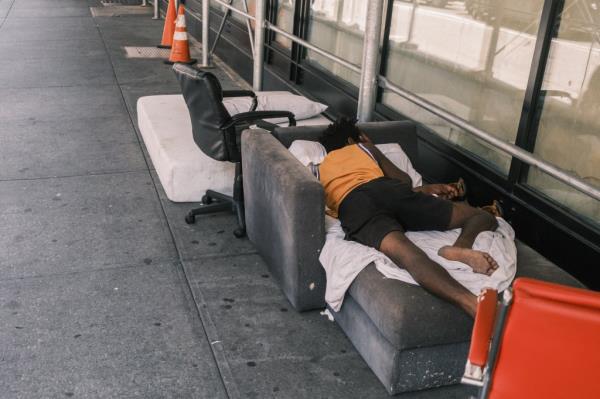 A man sleeps on a discarded couch on 30th street and Broadway in midtown Manhattan.