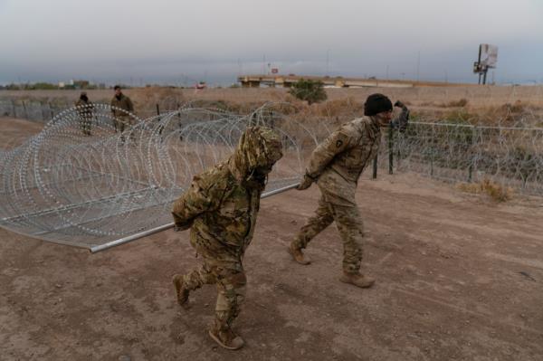 Soldiers deployed to El Paso drag new razor wire barriers.