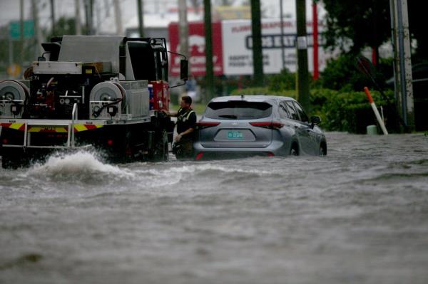 A tow truck assisting a stranded driver in flood waters.