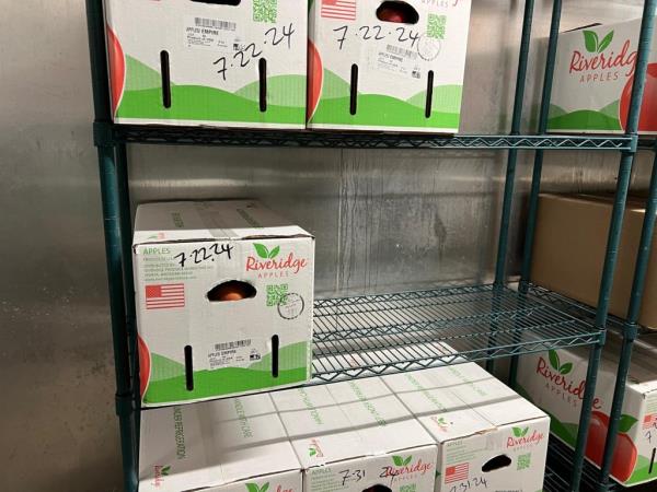 Boxes of apples stacked on a shelf in a walk-in fridge at a school in the North Bronx, District 10.