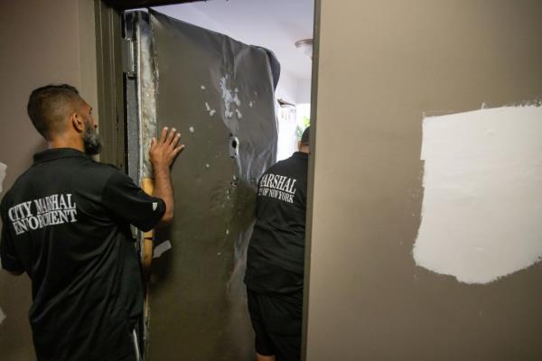 City marshals shown inspecting Lais' damaged door.