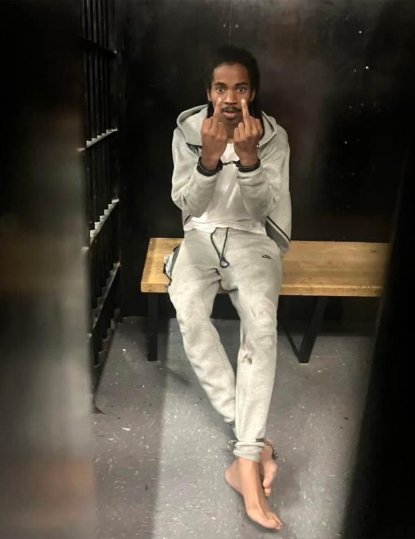 Joshua Dorsett, 22,  in his holding cell giving the middle finger with both hands while handcuffed and shackled