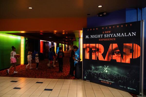 Kids walk around in a movie theater next to a poster for "Trap."