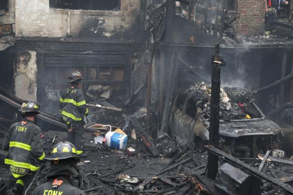 Firefighters near a car destroyed in the fire.