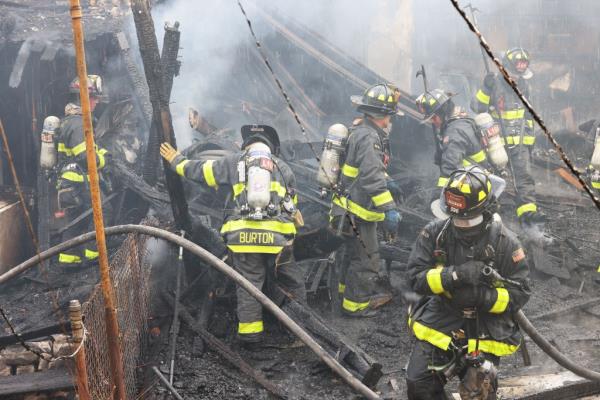 Firefighters standing in the backyards of burnt houses at Francis Lewis Blvd. in Queens, NY after managing to co<em></em>ntrol a 5-alarm fire