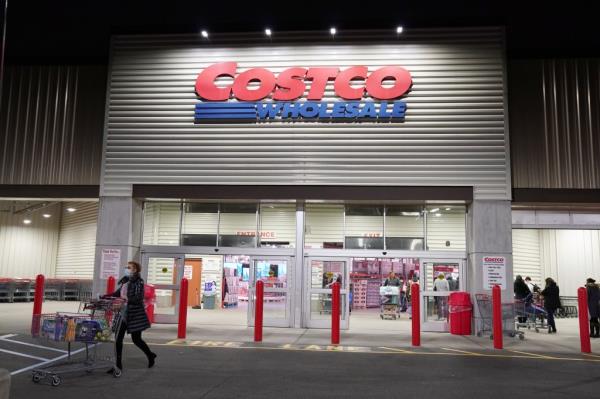 A general view of a Costco Wholesale store at night in Teterboro, NJ with a woman walking past