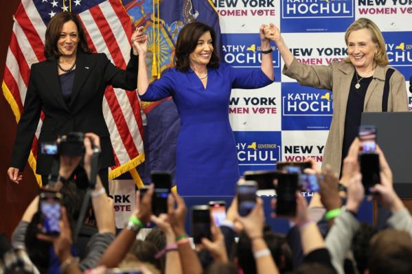 Vice President Kamala Harris, Governor Kathy Hochul, and Secretary Hillary Rodham Clinton holding up their hands at the co<em></em>nclusion of a New York Women Get Out The Vote rally