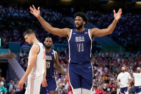 Joel Embiid, right, of the United States, reacts after scoring and being fouled as Filip Petrusev, of Serbia, walks away in a men's basketball game at the 2024 Summer Olympics, Sunday, July 28, 2024, in Villeneuve-d'Ascq, France.