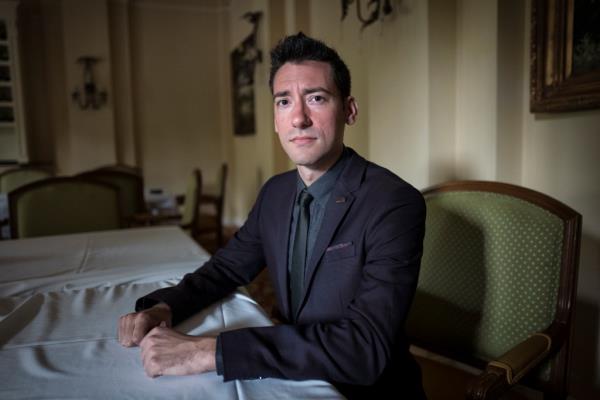 David Daleiden sitting at a table, looking anguished