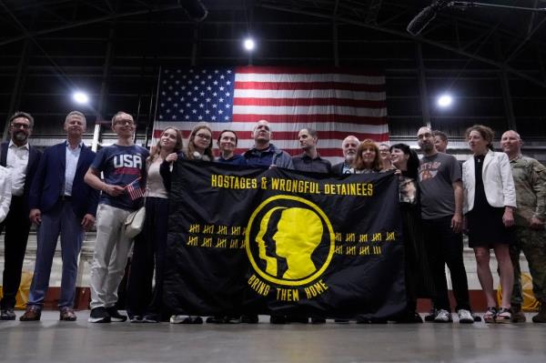 The freed priso<em></em>ners and their families posed with the Hostages and Wro<em></em>ngful Detainees flag.