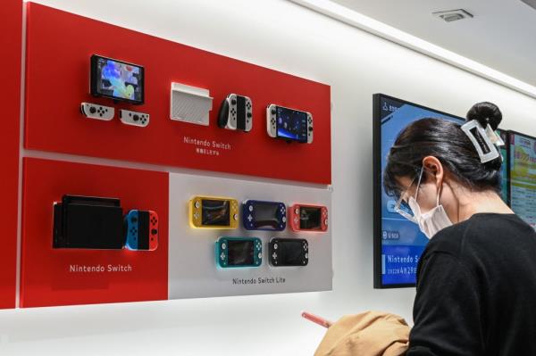 Woman wearing a mask while examining a Nintendo Switch display at a Nintendo store in central Tokyo