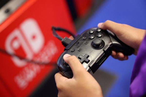 An attendee playing a video game on a Nintendo Switch co<em></em>nsole at Paris Games Week, 2023