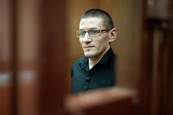 Robert Woodland, a Russia-born U.S. citizen, stands in a glass cage prior to a court hearing, Thursday, July 4, 2024, in Moscow, Russia. 