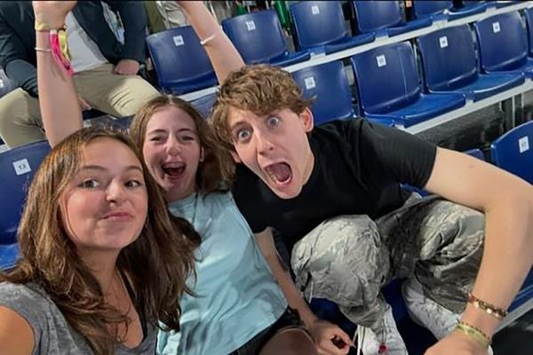 Twin sisters Tabitha Hodge Broderick and Marion Loretta Elwell Broderick take a selfie with brother James Wilkie Broderick while watching a beach volleyball match at the 2024 Olympic Games in Paris.