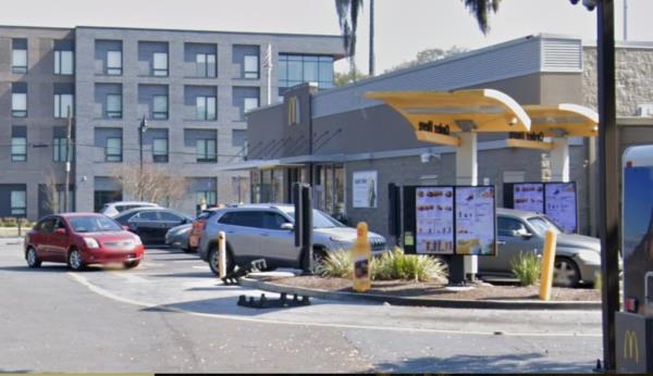 The exterior of a McDonald's restaurant can be seen with cars in the drive through