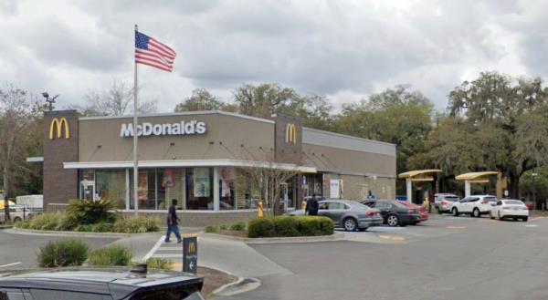 The exterior of a McDonald's restaurant can be seen with cars in the drive through