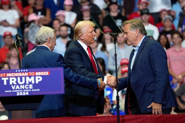 Former President Do<em></em>nald Trump shaking hands with Michigan Senate candidate, Mike Rogers, at a campaign rally in Grand Rapids, Michigan, 2024