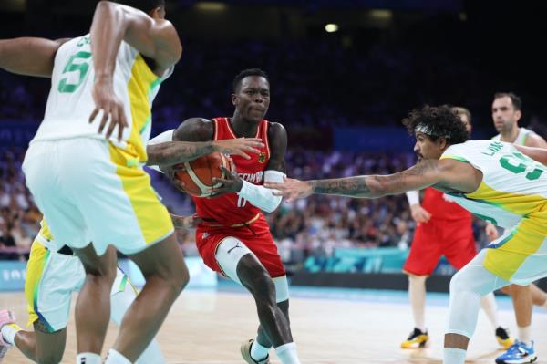 Germany's #17 Dennis Schroder (C) challenges Brazil's #99 Lucas Dias (R) in the men's preliminary round group B basketball match between Brazil and Germany during the Paris 2024 Olympic Games.