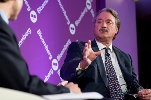 Alex Castellanos, wearing a suit, speaks to another man. He has a mustache and is pointing his hand forward.