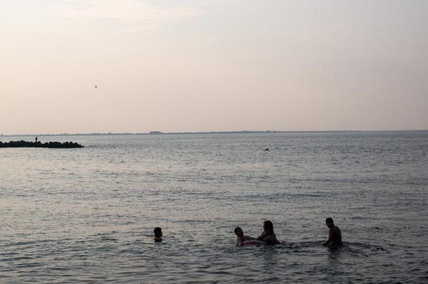 People swim and enjoy an early morning at the beach at Co<em></em>ney Island.