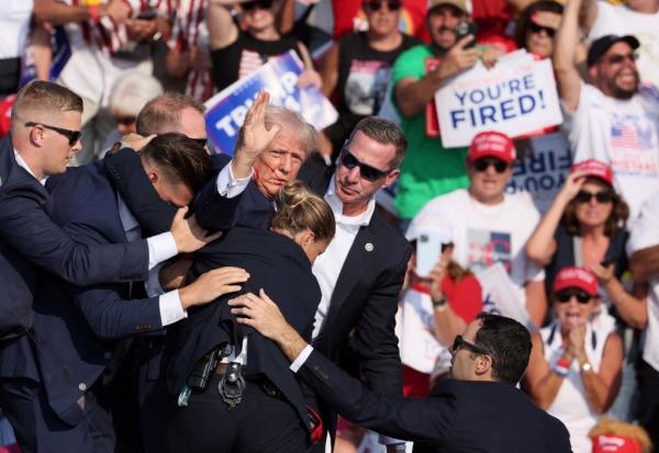 Do<em></em>nald Trump gestures with a bloodied face while he is assisted by U.S. Secret Service perso<em></em>nnel after he was shot in the right ear during a campaign rally at the Butler Farm Show in Butler, Pennsylvania.