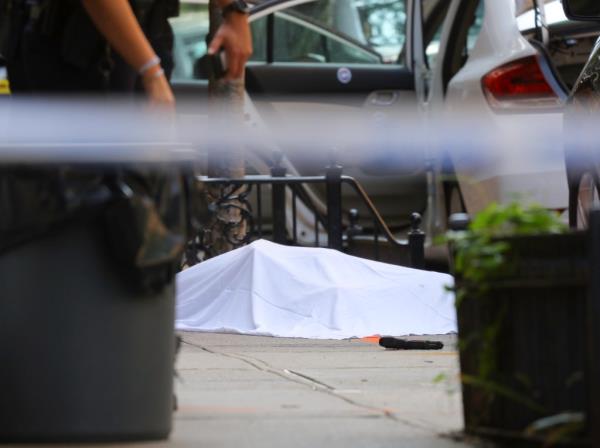 A body under a sheet after a shooting along a tree-lined Upper East Side street.